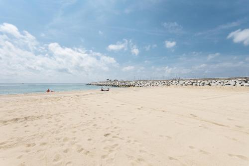 a beach with people laying on the sand and the ocean at Matarolux 1 in Mataró