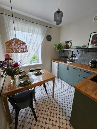 a kitchen with a table with a vase of flowers on it at House of the Sun in Ventspils