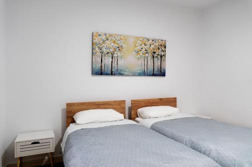 two beds in a room with a painting on the wall at Altozano la Victoria A 2 hab in Andújar