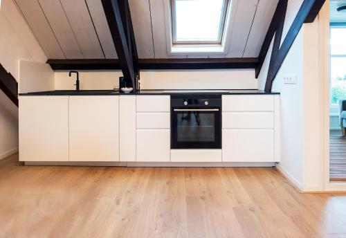 a kitchen with white cabinets and a black oven at B&B 'de Wenteltrap' in Makkum