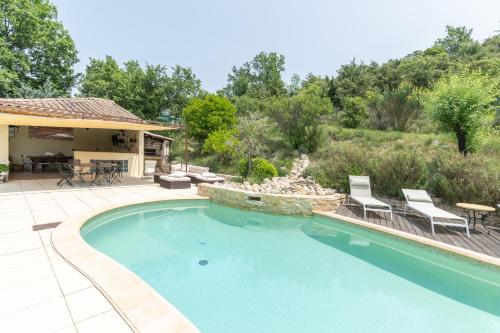 a swimming pool in a yard with chairs and a house at Gite Provençal in Grospierres