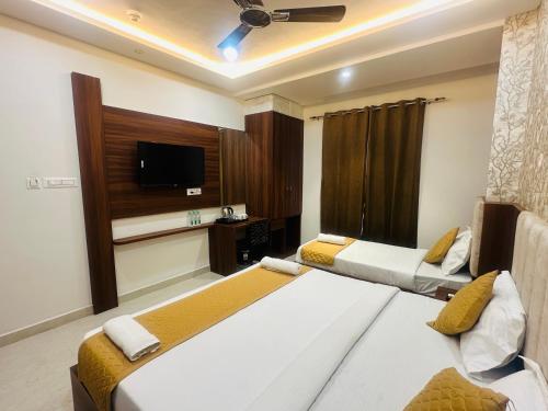 a bedroom with two beds and a flat screen tv at hotel deep palace in Varanasi