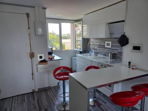 - une cuisine avec un comptoir et des chaises rouges dans l'établissement Nice Signature Caucade, à Nice