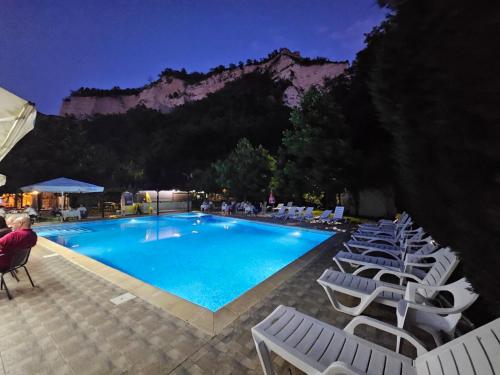 a swimming pool with lounge chairs and a mountain at Хотел Свети Трифон in Melnik