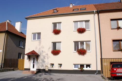 a white building with red flowers on the windows at Penzion Hustopeče in Hustopeče
