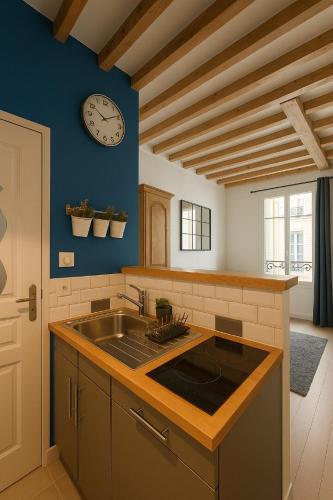 une cuisine avec un évier et une horloge murale dans l'établissement Havre de paix aux Champs-Elysées, à Paris