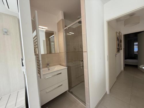 une salle de bain avec une douche, un lavabo et un miroir dans l'établissement maz poseidon 74, à Bormes-les-Mimosas