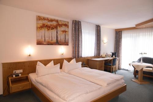 a bedroom with a large bed with white sheets at Hotel Breitenbacher Hof in Waldachtal