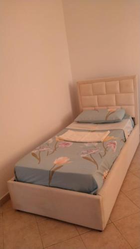 a bed with pink flowers on it in a room at Karaj Apartment in Tirane