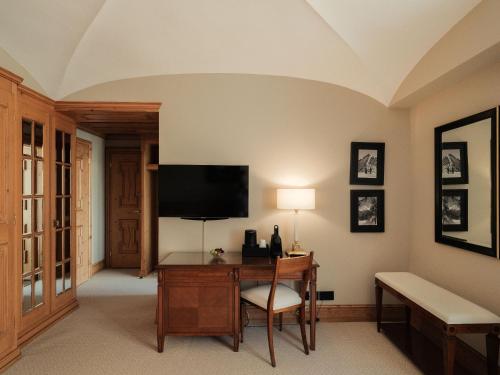 a room with a desk with a television on a wall at Kulm Hotel St. Moritz in St. Moritz