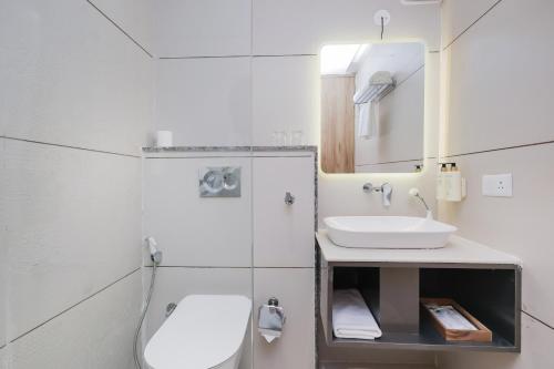 a bathroom with a sink and a toilet and a mirror at ECKO City Centre Rishikesh in Rishīkesh