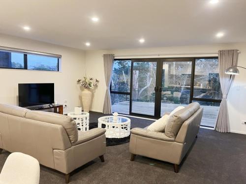 a living room with two couches and a television at 7th Heaven on Waikato River in Hamilton