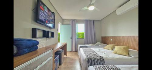a room with two beds and a tv on the wall at Suítes Aconchego in Capitólio