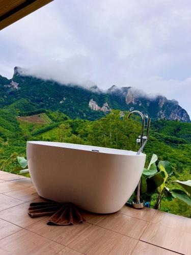 a bath tub sitting on a wooden floor with a mountain at Camping phutajoy Khaosok แคมป์ปิ้งภูตาจ้อยเขาศก in Ban Thung Lang Tham