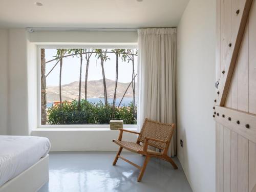a bedroom with a bed and a chair in front of a window at Villa Levi's in Mykonos