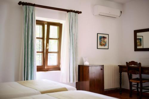 a bedroom with two beds and a desk and a window at Molino Del Santo in Benaoján