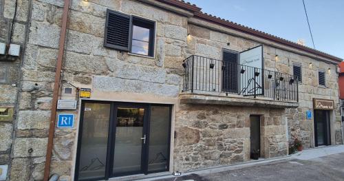 a stone building with a balcony and a window at Xanela Xures in Muiños