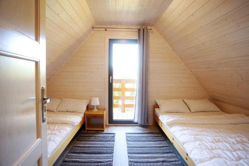 two beds in a small room with a window at Domki Tabaluga in Rusinowo