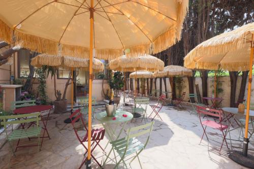 a group of tables and chairs under umbrellas at Hôtel Lou Juan in Juan-les-Pins