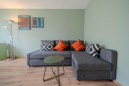 a living room with a gray couch and a table at Viktoria A12 by Arosa Vacations, Renoviertes App mit Bergblick im Zentrum in Arosa
