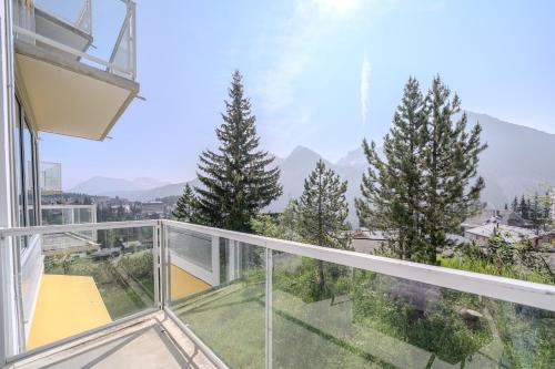 a glass balcony with a view of the mountains at Viktoria A12 by Arosa Vacations, Renoviertes App mit Bergblick im Zentrum in Arosa