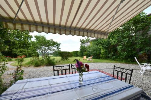 a table with a vase of flowers sitting under a pergola at Bernet in Labastide-Villefranche