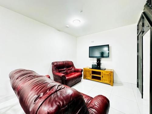 a living room with a leather couch and a television at Apartment in East Ham, London in London