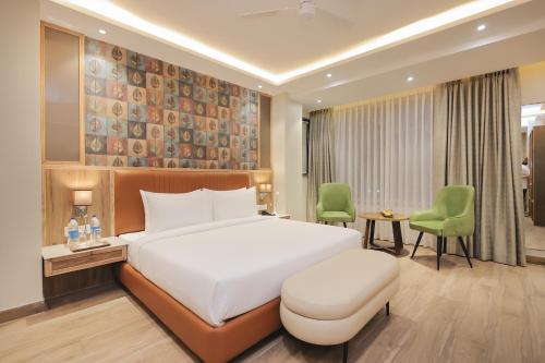 a bedroom with a large white bed and green chairs at ECKO City Centre Rishikesh in Rishīkesh