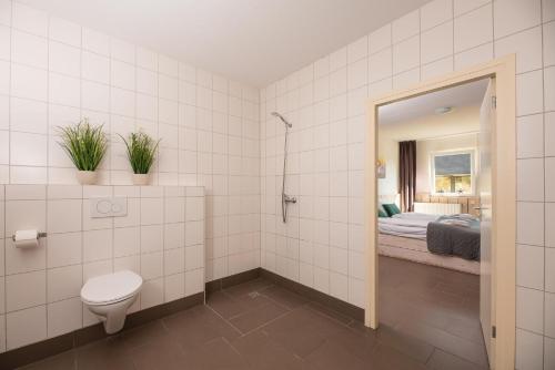 a bathroom with a toilet and a bed and a mirror at Familiehuis met Hottub + trekkershutten | 18 Pers. in Wilsum