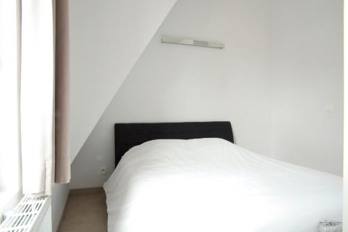 a bedroom with a white bed and a white wall at Place 2 stay in Ghent