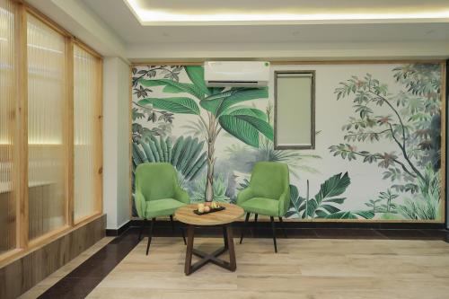 a room with two green chairs and a wall with a mural at ECKO City Centre Rishikesh in Rishīkesh
