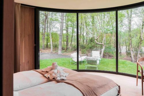 a bedroom with a bed in front of a window at LumiPod – Luxe glazen design‑pod in Wilsum