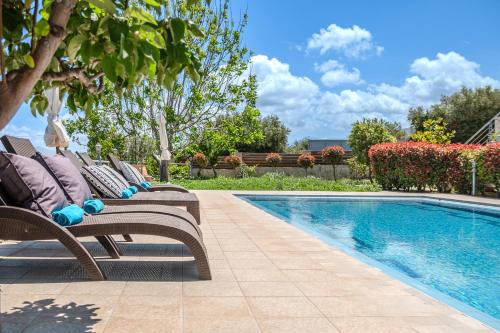 a pair of chairs sitting next to a swimming pool at Arios Lux Villa in Ayía Paraskeví