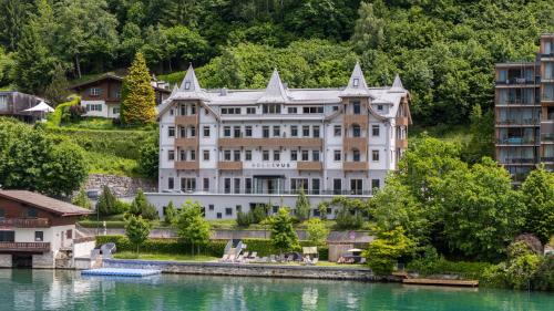 a large white building next to a body of water at Seehotel Bellevue by keyone in Zell am See