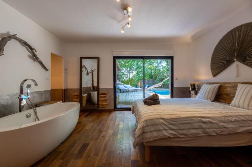 une chambre avec un grand lit et une baignoire dans l'établissement L'Éden - Maison d'architecte, Climatisée, Piscine, Home Cinéma, à Castres