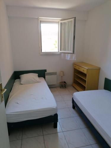 une chambre avec deux lits jumeaux et une fenêtre dans l'établissement T3 cavalaire dans résidence avec piscine, à Cavalaire-sur-Mer