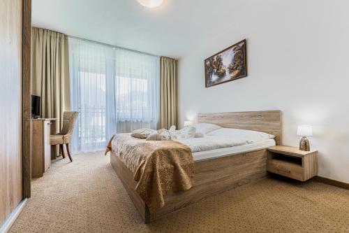 a bedroom with a large bed and a desk at Hotel Lesana in Vysoké Tatry