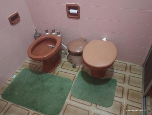 a bathroom with a toilet and two green rugs at Belíssima casa de Praia in Salinópolis
