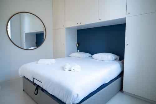 une chambre avec un grand lit blanc avec un miroir dans l'établissement GuestReady - Spacious Comfort with Sunny Garden, à Nice