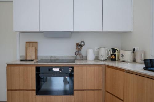 une cuisine avec des armoires blanches et un four noir dans l'établissement GuestReady - Spacious Comfort with Sunny Garden, à Nice