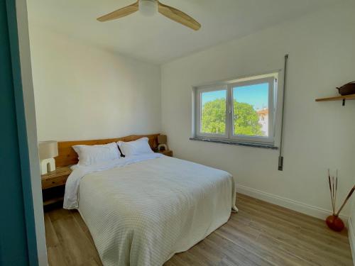 a white bedroom with a bed with a ceiling fan at Wild Souls Guesthouse in Ericeira