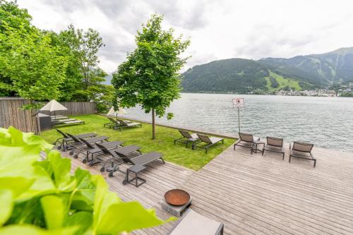 a row of chairs and tables on a deck next to a lake at Seehotel Bellevue by keyone in Zell am See
