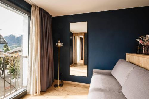 a living room with a couch and a mirror at The Post Apartments in Dobbiaco