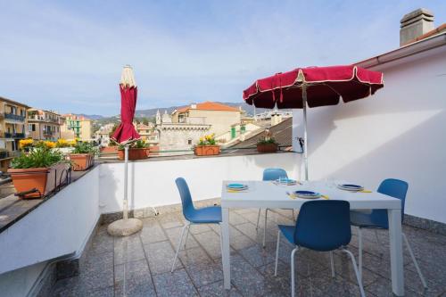 a white table and chairs on a balcony with an umbrella at the riviera attico terrazza in Lavagna