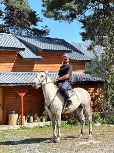 a man riding a horse in front of a cabin at Heshkili huts and cabins Svaneti in Keshkili