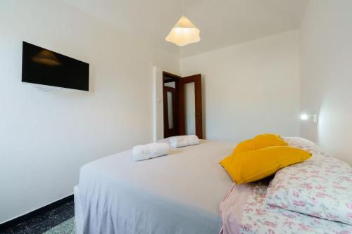 a white bedroom with a bed with yellow pillows at the riviera attico terrazza in Lavagna