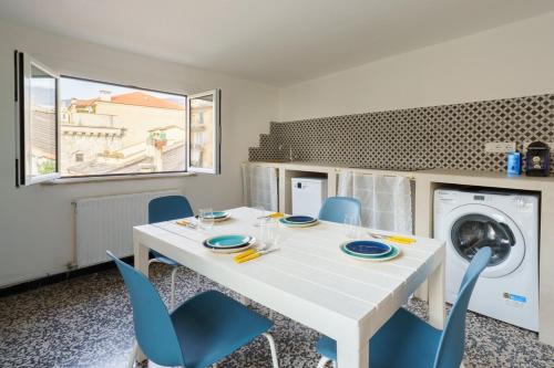 a dining room with a white table and blue chairs at the riviera attico terrazza in Lavagna
