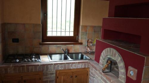 a kitchen with a sink and a brick fireplace at Casa Vacanze Le Primule in Peveragno