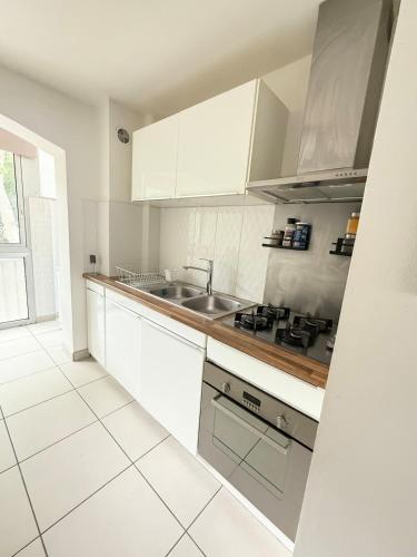 une cuisine blanche avec des armoires blanches et un évier dans l'établissement Le Tilleul F2 cosy proche centre, à Montpellier