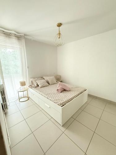 - une chambre blanche avec un lit dans une pièce dotée d'une fenêtre dans l'établissement Le Tilleul F2 cosy proche centre, à Montpellier